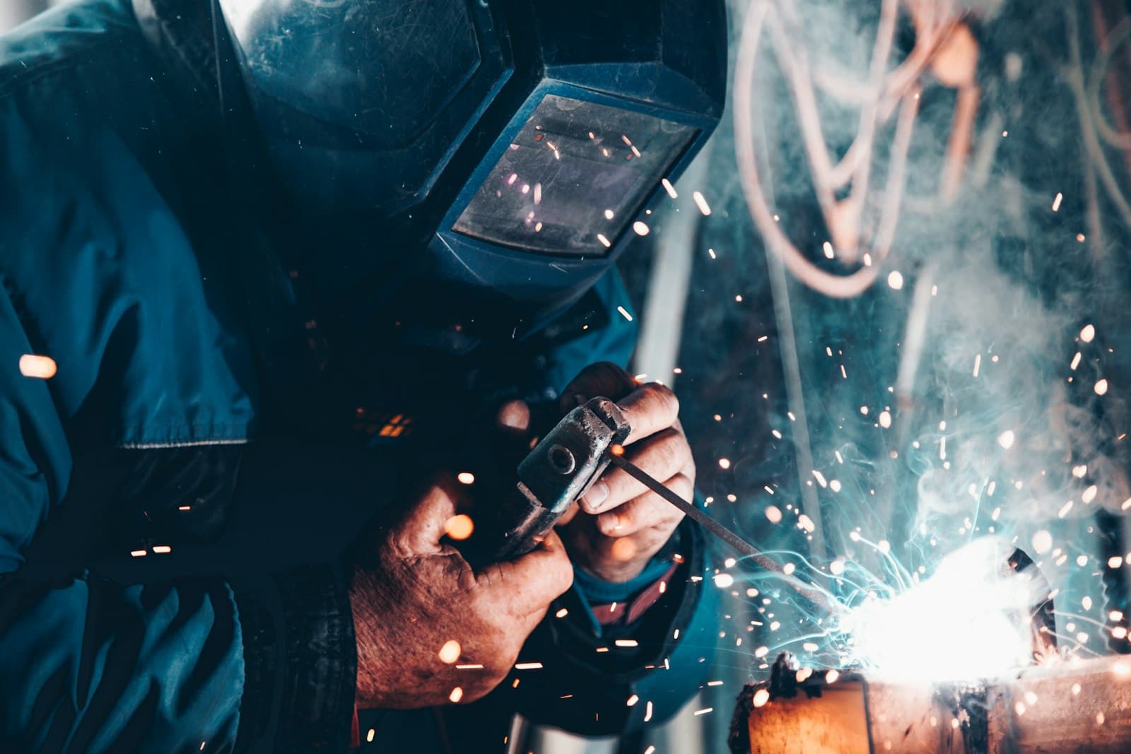 Soldador trabajando con chispas y máscara de protección